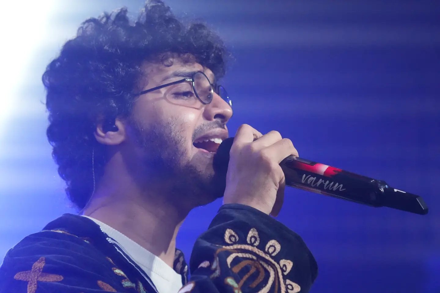 Varun Jain singing live under blue stage lights